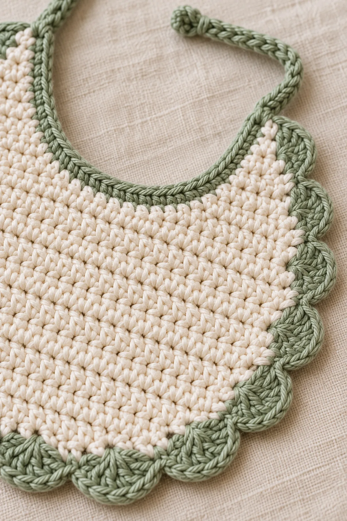 Close-up of stitch texture and finishing details on easy crochet baby bib with scalloped edge